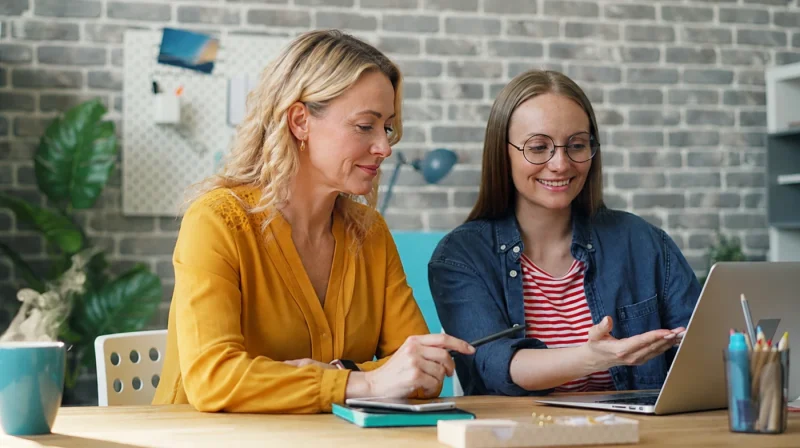 2 Frauen am Laptop haben Kontakt zueinander und arbeiten zusammen.